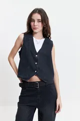 Chaleco denim negro con corte moderno, escote en V y cierre frontal con botones metálicos.