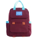 Mochila color borgoña con detalles en celeste y naranja, con dos bolsillos frontales con cierre de hebilla y etiqueta con la frase "You are the best version of yourself".