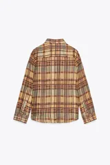 Camisa de mujer confeccionada en ramio 100% con estampado a cuadros en tonos beige, marrón y celeste. Tiene cuello solapa, manga larga con puños, bolsillo de plastrón en el delantero, bajo redondeado y cierre frontal con botones.