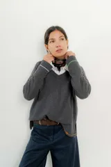 Sweater de punto gris con cuello en V y ribetes en contraste.