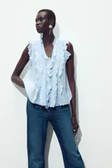 Blusa celeste sin mangas con escote en V y volantes.