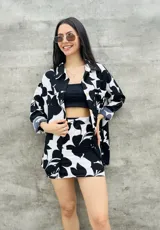 Camisa de manga larga en tono negro con estampado de flores en blanco, con cierre frontal y diseño holgado.