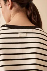 Vestido corto a rayas horizontales blancas y negras, con cuello redondo y mangas cortas. Presenta un estampado frontal con la palabra "L'AMOUR" en rojo y una flor roja. Tiene un tajo lateral en el ruedo.