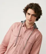 Camisa manga larga color rosa con capucha gris, cierre con botones, bolsillos frontales y corte recto.