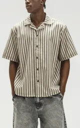 Camisa oversize de manga corta con cuello abierto y estampado a rayas verticales en tonos verde y beige.