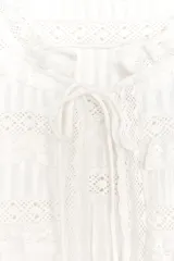 Top de tejido satinado color blanco, con cuello redondo, manga corta y detalle de puntilla a tono. Cierre frontal con lazadas.