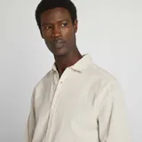 Camisa beige con rayas verticales finas, de corte clásico, manga larga y cuello camisero.