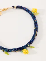 Collar corto con cordón azul bordado con mostacillas de vidrio y dijes de limones amarillos y hojas verdes bordados a mano con mostacillas.