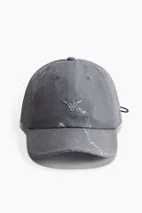 Gorra gris con estampado jaspeado, logo plateado en el frente, ojales bordados y cordón elástico ajustable en la parte trasera.
