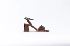 Sandalias de cuero color bronce con textura tipo cocodrilo, con tira delantera ancha y tira fina con hebilla al tobillo. El tacón es ancho y cuadrado.