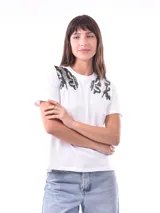 Remera blanca de algodón con cuello redondo y estampado con apliques brillantes en los hombros.