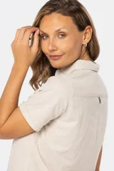 Camisa color beige de lino y algodón, de manga corta, con cuello clásico, medio abotonado y dos bolsillos en el pecho.