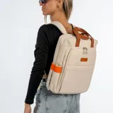 Mochila negra con detalles en naranja y marrón. Tiene dos asas cortas marrones en la parte superior y dos bolsillos laterales color naranja.