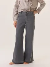 Pantalón de jean color gris oscuro, tiro alto, con pierna ancha y acampanada. Presenta costuras a contratono y bolsillos laterales.