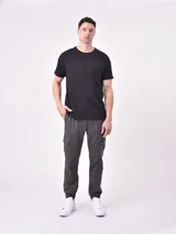 Pantalón jogger gris oscuro con cintura elástica ajustable con cordón, bolsillos laterales y bolsillo cargo con solapa en la pierna. Puños elásticos en los tobillos.