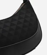 Bolso baguette pequeño color negro, con textura embossed y estampa triangular. Tiene asa mediana ajustable y cierre de cremallera.