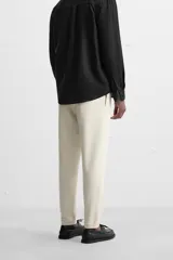 Pantalón negro de corte cropped, con cintura elástica ajustable con cordón, bolsillos laterales y traseros de vivo. El bajo tiene terminación con vuelta.