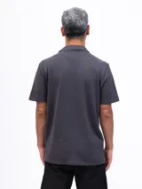 Camisa de manga corta color azul marino, confeccionada en tejido piqué de algodón. Presenta cuello cubano y cierre frontal de botones. Incluye un bolsillo de parche en el pecho izquierdo.