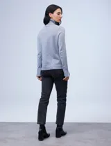 Polera de punto fino marca Nienty, color blanco, con cuello alto volcado y mangas largas con detalle de tajo en los puños.