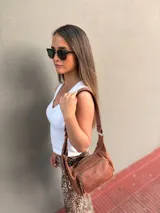 Cartera bandolera de cuero color marrón, con correa ajustable y bolsillo externo con cierre.