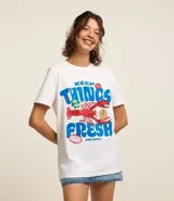 Remera blanca de algodón con corte alargado, cuello redondo y mangas cortas. Estampa frontal con una langosta y la frase "Keep Things Fresh".