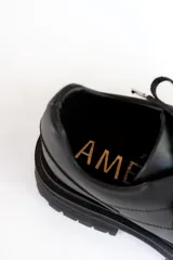 Zapato acordonado de cuero marrón con suela track negra.