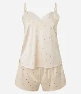 Conjunto de pijama compuesto por un top de satén color crema con lunares marrones, breteles finos regulables y escote en V con encaje, y un short con cintura elástica y estampado de lunares a juego.