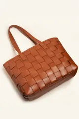 Cartera tipo tote bag de cuero vacuno trenzado a mano, con diseño de tejido ajedrez. Cuenta con doble asa de hombro y cierre superior.