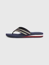 Ojotas Tommy Hilfiger color azul marino con tiras trenzadas en dorado y detalles distintivos de la marca.
