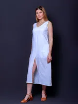 Vestido blanco de lino, corte recto, largo midi y tajo frontal. Sin mangas y con escote en V.