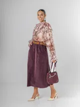 Falda midi de micro pana color morado oscuro, de corte recto y cintura elastizada. Incluye un cinturón desmontable de cuero marrón.