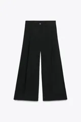 Pantalón cropped marrón de tiro medio y pierna ancha, confeccionado en hilatura con mezcla de lyocell. Presenta trabillas en la cintura, bolsillos laterales y pinzas en el delantero. Cierre frontal con cremallera y botón.
