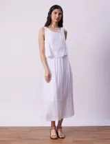 Vestido largo blanco de crepe, con escote redondo y sobrecapa con ruedo de broderie. Corte en la cintura con punto smock.