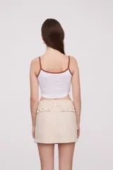 Musculosa cropped blanca con tirantes marrones, estampado de playa con palmeras, sol y flores.