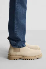 Bota Chelsea color beige de cuero, con elásticos laterales, tiradores delanteros y traseros, y suela track.