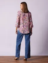 Blusa estampada con flores en tonos rosa, naranja y azul marino. Tiene escote en V con detalle de pliegues y mangas 3/4 con volados.