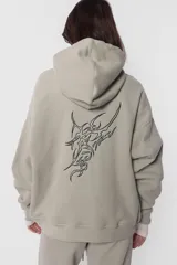 Buzo hoodie de frisa color beige, de silueta oversize, con puños y cintura de rib al tono, capucha forrada en su interior, bolsillo canguro, cordones con ojalillos y punteras metálicas personalizadas con marca, tanca para regular cordones, remaches en boca de bolsillo y bordado en espalda a contratono.