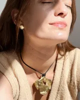 Set de dos piezas de joyería para la oreja: un arete de botón con forma orgánica irregular y un ear cuff a juego, ambos de metal dorado con acabado martillado.