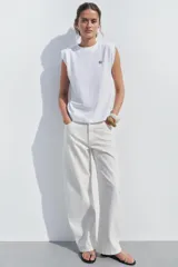 Camiseta blanca de algodón con cuello redondo y manga sisa con hombreras. Detalle de aplicación metálica ZA en el delantero.