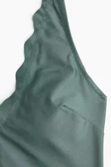 Traje de baño entero color verde con escote en V festoneado, breteles ajustables y copas con relleno extraíble. Cobertura media en la parte de atrás y forro completo.