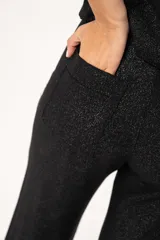 Pantalón negro de lino imperial con lurex, tiro medio, corte palazzo, bolsillos delanteros y traseros, y cierre frontal con cremallera y botón.