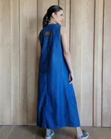 Vestido largo color crudo, sin mangas y con escote en V. Presenta aberturas laterales en el ruedo y bolsillos laterales a la altura de la cadera.