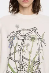 Remera negra de algodón con cuello redondo y manga corta. Estampado frontal con diseño floral abstracto en tonos rosa y marrón.