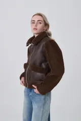 Campera estilo aviador con cuerpo de eco-cuero marrón oscuro y mangas y cuello de corderito (teddy) marrón. Presenta cierre frontal metálico y dos bolsillos frontales con solapa de corderito.