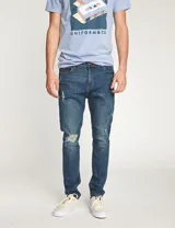 Pantalón de jean azul con roturas en las rodillas, corte slim fit.