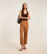 Pantalón de vestir azul marino, de corte zanahoria, con cinturón fino negro con hebilla dorada.