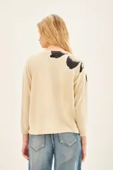 Sweater color crema con estampado de flor en tonos grises y negros en el frente.