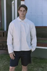 Campera color crema de corte recto, con cuello clásico, cierre con botones a presión, puños abotonados y bolsillos frontales tipo parche.