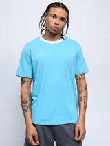 Remera color arena de corte clásico con cuello redondo ribeteado en blanco y logo Umbro estampado en el pecho.