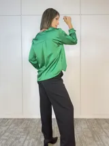 Blusa verde oliva de satén con cuello en V y mangas largas con puños abotonados.